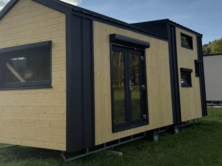 Domek modułowy HORIZON z jasną drewnianą elewacją i czarnymi obróbkami na trawiastej działce